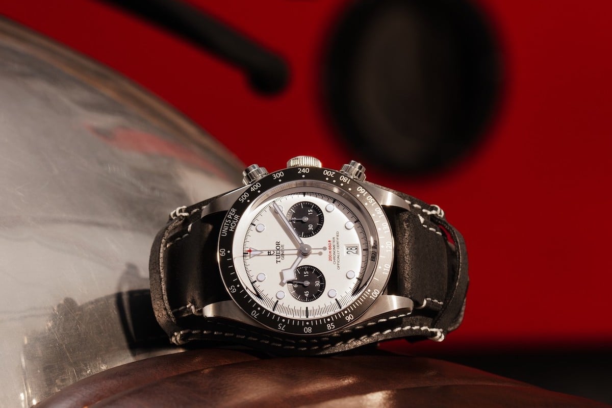 Omega chronograph watch on leather, red background.