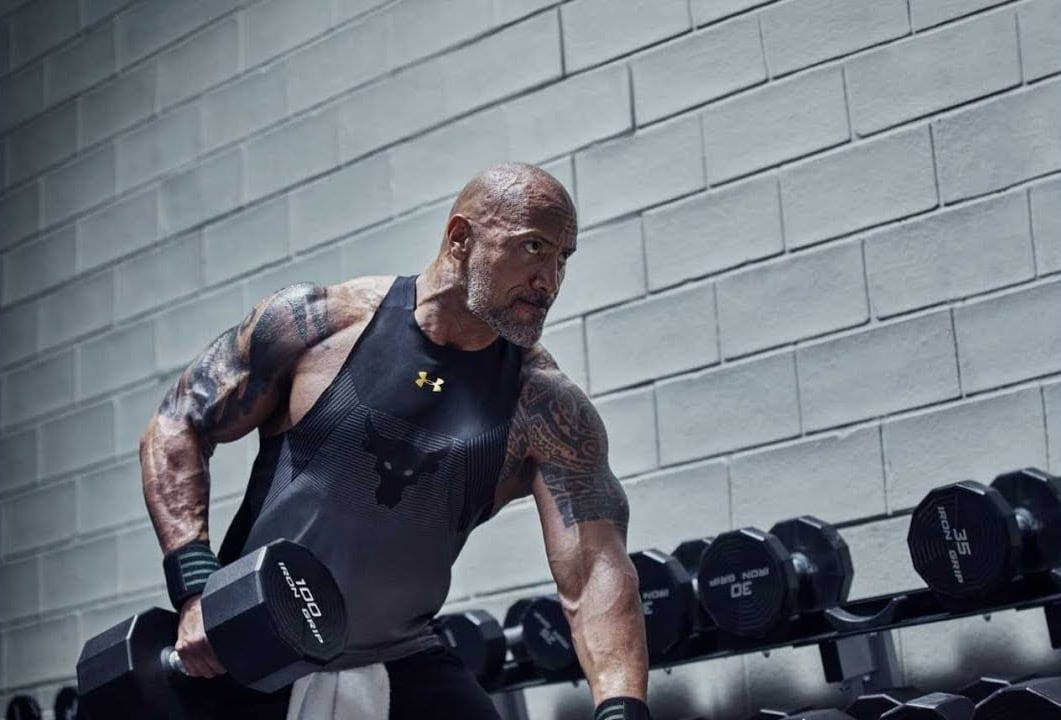 Tattooed man lifting dumbbell, gym.