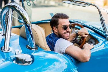 Man in blue vintage Baume Mercier Cobra, smiling with sunglasses.