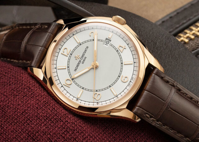 Vacheron Constantin gold watch on burgundy fabric.