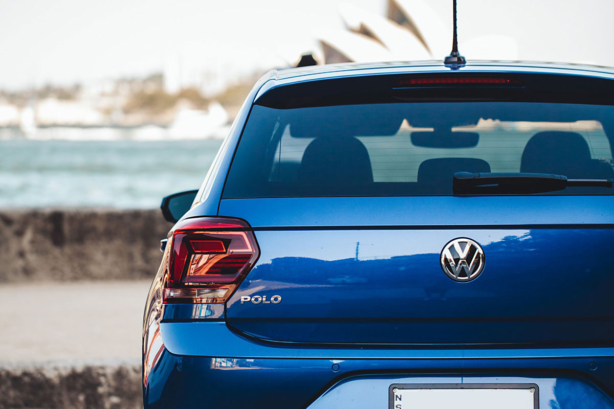 Blue Volkswagen Polo parked by iconic Australia view.