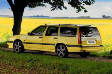 Euro station wagon parked by yellow flowers.