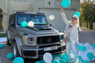 Person near silver SUV with teal balloons.