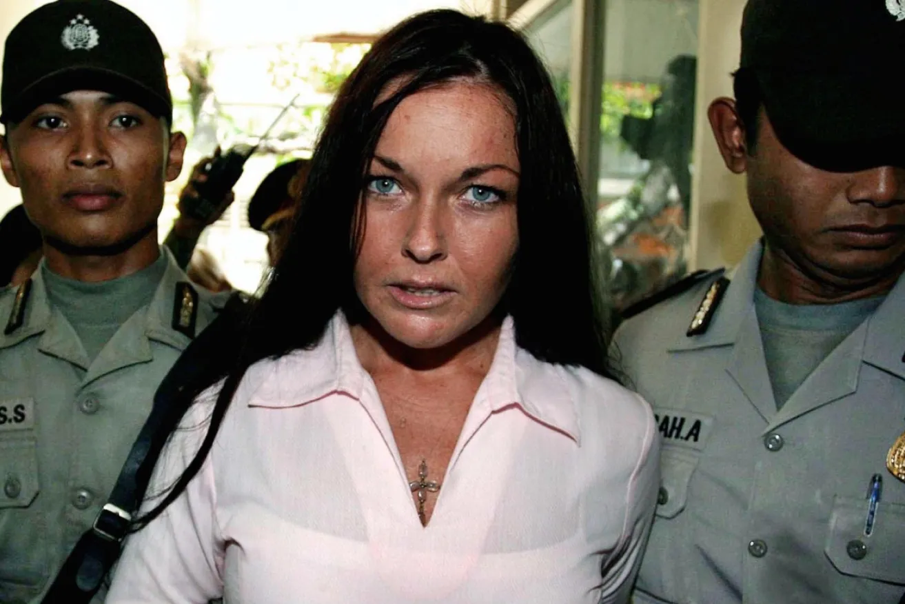 A woman in pink escorted by officers in Indonesia.