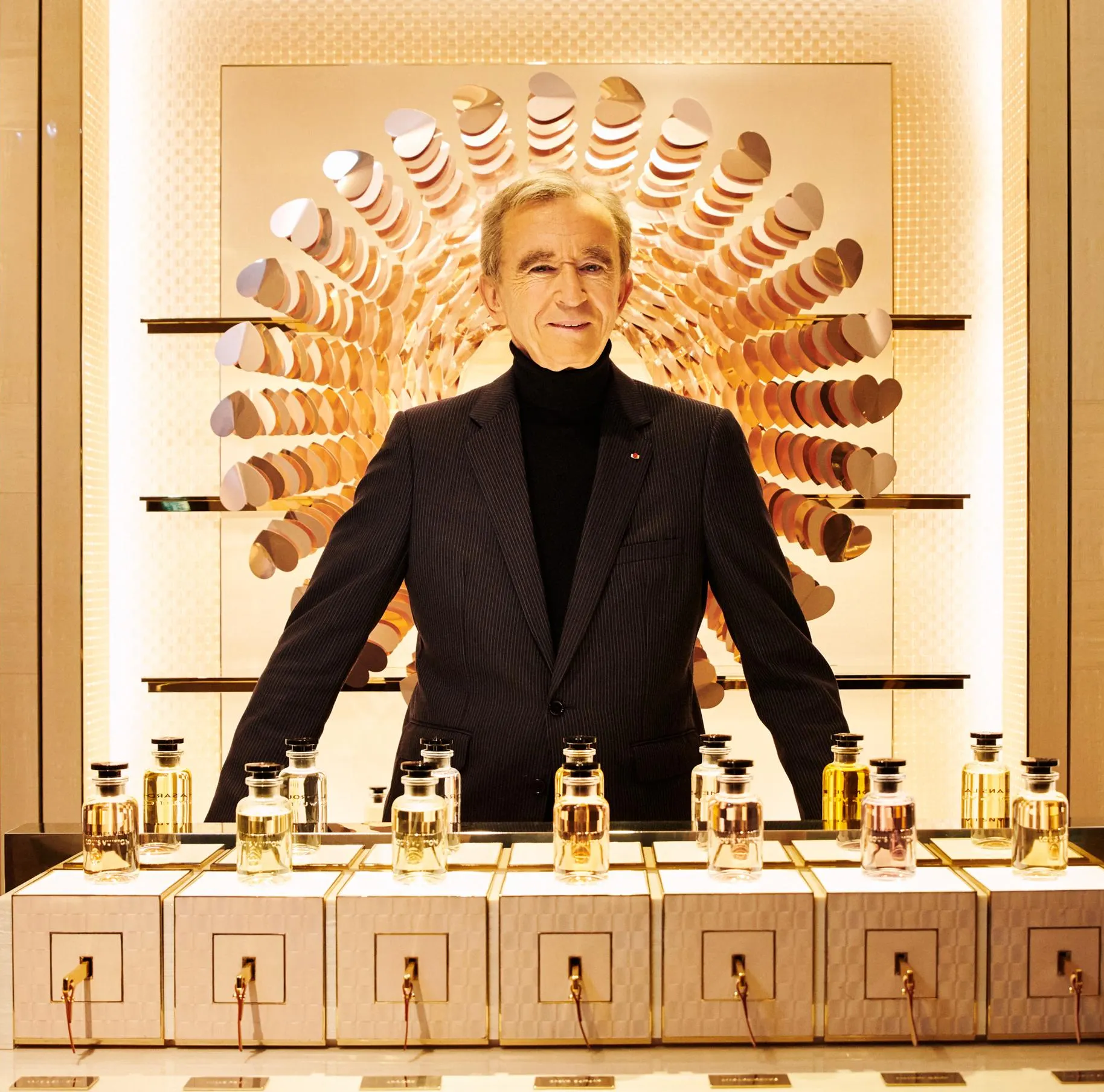 Man in suit displays perfume; elegant LVMH style.