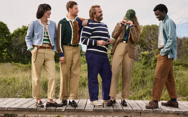 Five people in designer outfits chat outdoors.